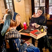 A fortune-teller reads cards at a medieval dinner.