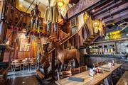 Vista de la escalera de Le Roy d'Espagne, con esculturas de madera, un caballo disecado, marionetas colgadas del techo y escalones de madera.