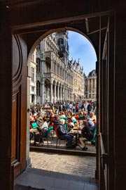 Vista desde el interior de Le Roy d'Espagne hacia la soleada terraza y la Grand-Place al fondo.